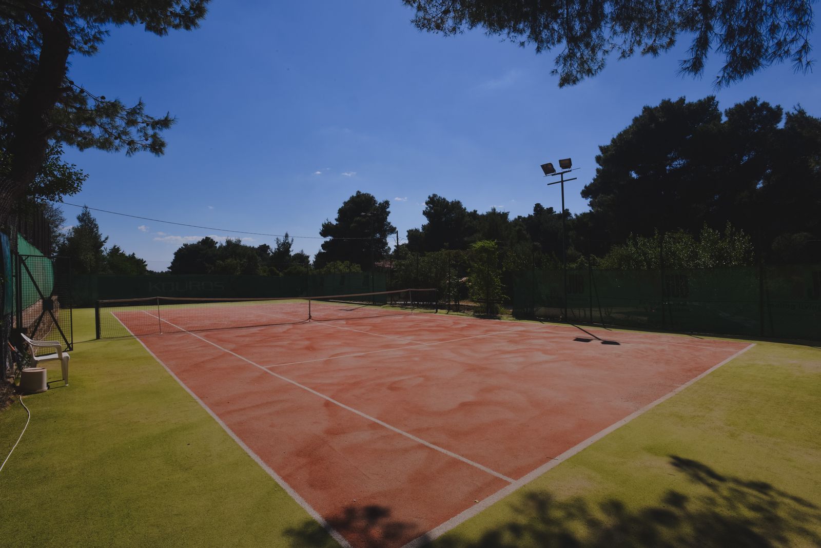 The turf court in summer, framed by pines